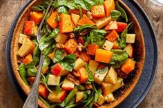 a salad with spinach, carrots and other vegetables in a bowl on a wooden table