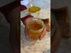 a person pouring honey into a glass jar