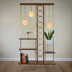 a book shelf with three lights and a potted plant next to it on top of a hard wood floor