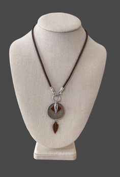 Antiqued silver and copper charms and discs dangle from soft brown suede cord. Measures 17 .5 inches and closes with a lobster clasp and 2.5 inch extender. Great for everyday attire and perfect piece for layering. Brown Metal Jewelry With Adjustable Cord, Artisan Brown Necklace With Adjustable Cord, Brown Necklace With Adjustable Cord And Round Pendant, Brown Leather Necklace With Adjustable Length, Nickel-free Brown Metal Necklace, Leather Cord Necklace, Leather Corded Necklace, Suede Cord, Disc Pendant