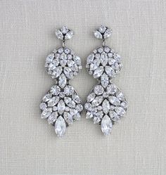 two pairs of earrings with crystal stones on them, one is white and the other is clear