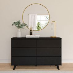 a black dresser with a mirror and plants on it in front of a white wall