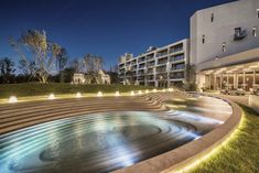 an illuminated fountain in front of a building at night