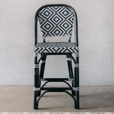 a black and white chair sitting on top of a cement floor next to a wall