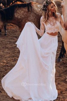 a woman in a white dress standing next to two horses