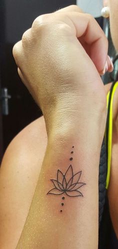 a woman's arm with a small tattoo on the wrist and a lotus flower