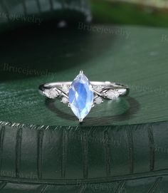 an oval shaped blue topazte and diamond ring sits on a green leather surface