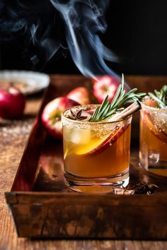 two glasses filled with apple cider on top of a wooden table