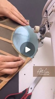 a woman is using scissors to sew on a piece of fabric with the help of a sewing machine