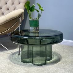 a glass table with a potted plant on top and a chair in the background