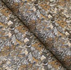 an image of a flowery fabric with gold and grey flowers on brown background, closeup