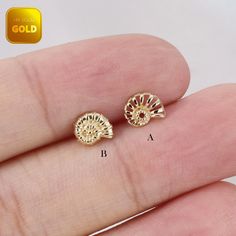 small gold plated stud earrings with filigrees in the middle, on a hand