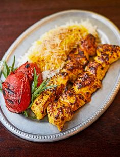 a plate with chicken, rice and tomatoes on it