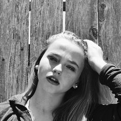 black and white photograph of a woman leaning against a wooden fence with her head in her hands