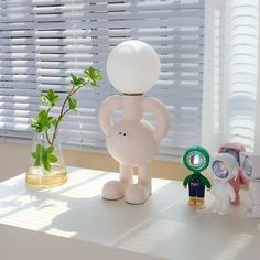 three small toys sitting on top of a table next to a vase with a plant in it