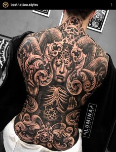 the back of a man's body with tattoos on it and an angel above his head