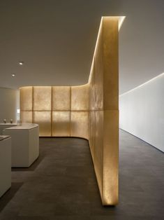 an empty room with white counter tops and gold colored panels on the wall behind it