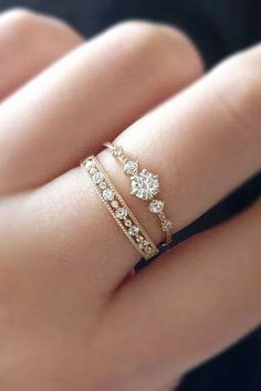 a woman's hand with two gold rings on it and one diamond ring in the middle