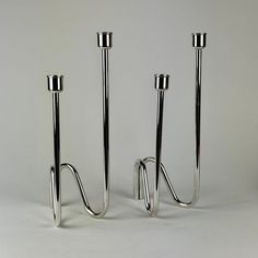 two metal candlesticks sitting next to each other on a white surface with no one around them