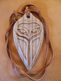 a wooden ornament on a brown leather surface with a tan ribbon around it