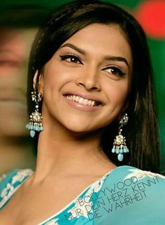 a woman in a blue and white dress smiling at the camera with her eyes closed