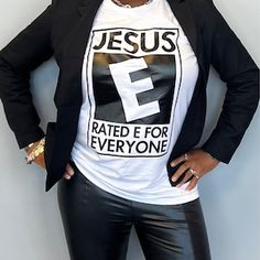 a woman in black leather pants and a white jesus t - shirt is standing with her hands on her hips