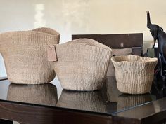 three woven baskets sitting on top of a wooden table next to a black cat statue