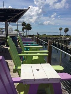 colorful wooden chairs sitting on top of a pier