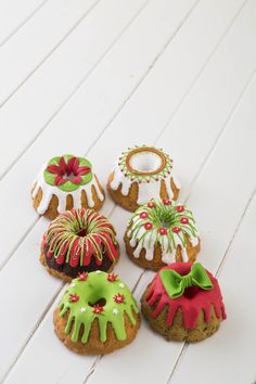 six decorated cookies sitting on top of a white wooden table next to each other with green and red icing