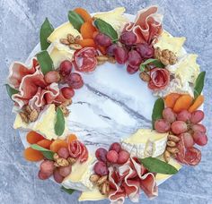 a cake decorated with fruit and nuts on top of a marble slab topped with leaves