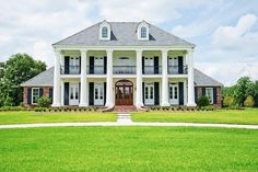 a large white house with black shutters on the front and second story, surrounded by lush green grass