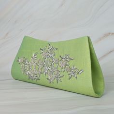 This pastel green colored boat shape hand bag  in silk fabric fits all occasions and attires. The handcrafted  bag with intricate zardozi work and onyx stone makes it a fit for all occasions. The metal string makes it long lasting and has enough room to carry essentials and more.. This beautifully embroidered Shoulder Bag is hand crafted using zardozi technique. Zardozi work is done carefully stitching layer upon layer of threads and metal wires and embellished with precious or semi precious gemstones making each piece one of its kind. Size cm:  30x14x4 Utility: Shoulder Bag / Hand Clutch Material: Silk Fabric, Metal Thread Base Color: green Pockets: Single Care : Dry clean only Please Note - This product has been crafted by hand and may have slight irregularities or imperfections in color Formal Rectangular Bag With Resham Embroidery, Elegant Resham Embroidered Evening Bag, Green Embellished Bag For Events, Elegant Wedding Evening Bag With Resham Embroidery, Elegant Party Clutch With Resham Embroidery, Festive Evening Clutch With Resham Embroidery, Green Luxury Embellished Clutch, Luxury Green Embellished Clutch, Elegant Resham Embroidery Bags For Festive Season