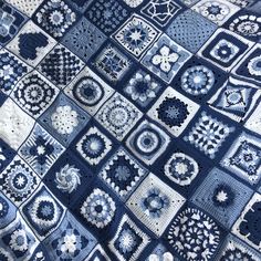 a blue and white crocheted blanket with many squares on top of it,