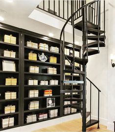 a spiral staircase in front of a bookshelf filled with lots of books and papers