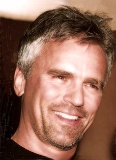 a close up of a person wearing a black shirt and smiling at the camera with a smile on his face