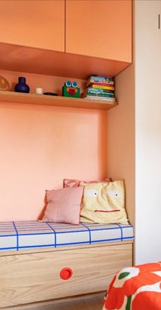 a bedroom with pink walls and a bed that has a blue stripe on the bottom