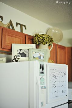 a refrigerator with magnets and pictures on the door, sitting in a kitchen next to wooden cabinets