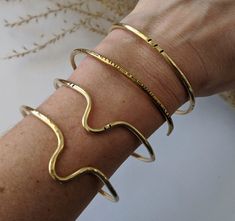 "Another versatile classic, handcrafted from raw brass.  Wear one alone for a minimalist touch, or stack them up for a bolder bohemian look. Choose from 4 styles of cuff, or make it a set of 4 Find your perfect fit: All cuffs are adjustable, but ordering the correct size will ensure your most comfortable fit. Measure the circumference of your wrist by wrapping a flexible tape measure around the wrist just below the wrist bone, making note of where the tape overlaps.  Use the chart below to determine your size: S - 5 - 6\" M - 6 - 6.5\" L - 6.5 - 7\" XL - 7 - 8\" For a looser bangle-style bracelet consider sizing up one or two sizes. Please note that because each piece is handmade to order, yours may differ slightly from the ones pictured above but will of course stay true to them in essenc Minimalist Handmade Brass Bangle, Handmade Minimalist Brass Bangle, Handmade Gold Cuff Bracelet For Everyday, Everyday Handmade Gold Cuff Bracelet, Gold Handmade Minimalist Cuff Bracelet, Minimalist Everyday Brass Bangle, Everyday Minimalist Brass Bangle, Modern Brass Bangle For Everyday Wear, Everyday Minimalist Handmade Cuff Bracelet