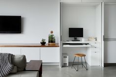 a flat screen tv mounted to the side of a wall next to a wooden table