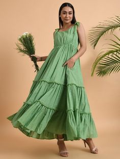 A flared and flounced tiered maxi dress with tie-up belts on the shoulder, elasticated waistline, and attached soft cotton lining. Garment measurements (in Inches): Small: Bust - 39", Waist - 29", Hip - Flared Medium: Bust - 42", Waist - 32", Hip - Flared Large: Bust - 45", Waist - 35", Hip - Flared Length: 50-55 inches (Length can be adjusted with shoulder straps) Fabric: Cotton Dobby Color: Green Fit: Model height is 5'7" Model is wearing a size S Loose and comfortable fit. Instructions: Hand Spring Cotton Maxi Dress With Ruffled Straps, Cotton Maxi Dress With Ruffle Hem For Vacation, Cotton Sundress Maxi With Ruffles, Casual Ruffled Floor-length Maxi Dress, Casual Floor-length Ruffled Maxi Dress, Casual Floor-length Maxi Dress With Ruffles, Casual Cotton Maxi Dress With Ruffled Straps, Tiered Cotton Maxi Dress With Ruffle Hem, Cotton Dress With Tie Straps And Tiered Skirt