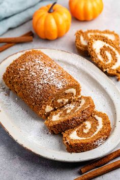 cinnamon roll on a plate with cinnamon sticks and pumpkins in the backgroud