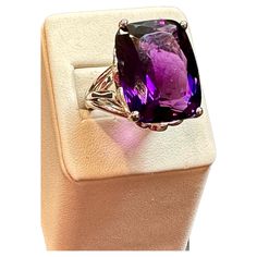 This vintage cocktail ring is a stunning piece of jewelry that features a huge 38 carat cushion-cut natural amethyst set in platinum. The amethyst measures 17 x 21 mm, giving the ring a substantial size and presence. The weight of the ring with the stone is 23.8 grams, adding to its luxurious feel and value. The beautiful work on the side of the band and on the side of the ring adds to the unique beauty of this piece. The craftsmanship is evident in every detail, making this ring a true work of Amethyst Cocktail Ring, Cocktail Vintage, Amethyst Set, Vintage Cocktail Ring, Vintage Cocktail, Unique Beauty, Ring Ring, Bolivia, Cocktail Ring