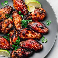 grilled chicken wings with garnishes and lemon wedges on a plate