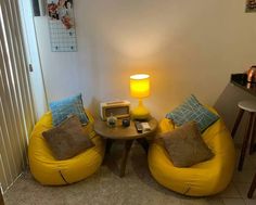 two yellow bean chairs sitting next to each other in front of a table and lamp