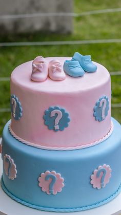 two tiered cake decorated with blue and pink fondant baby booties on top