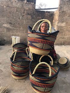 a woman sitting in front of baskets on the ground