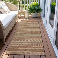 an outdoor area rug on a wooden deck next to a couch and potted plant