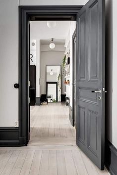 an open door leading to a hallway with white walls and wood floors in the center