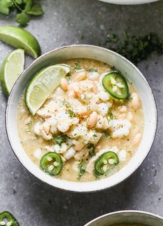 two bowls filled with soup and garnished with limes