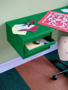 a green desk with scissors and paper on it next to a chair in a room